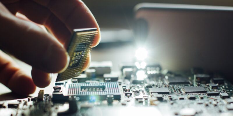 A closeup of a technician’s hand placing a computer processor on a motherboard.