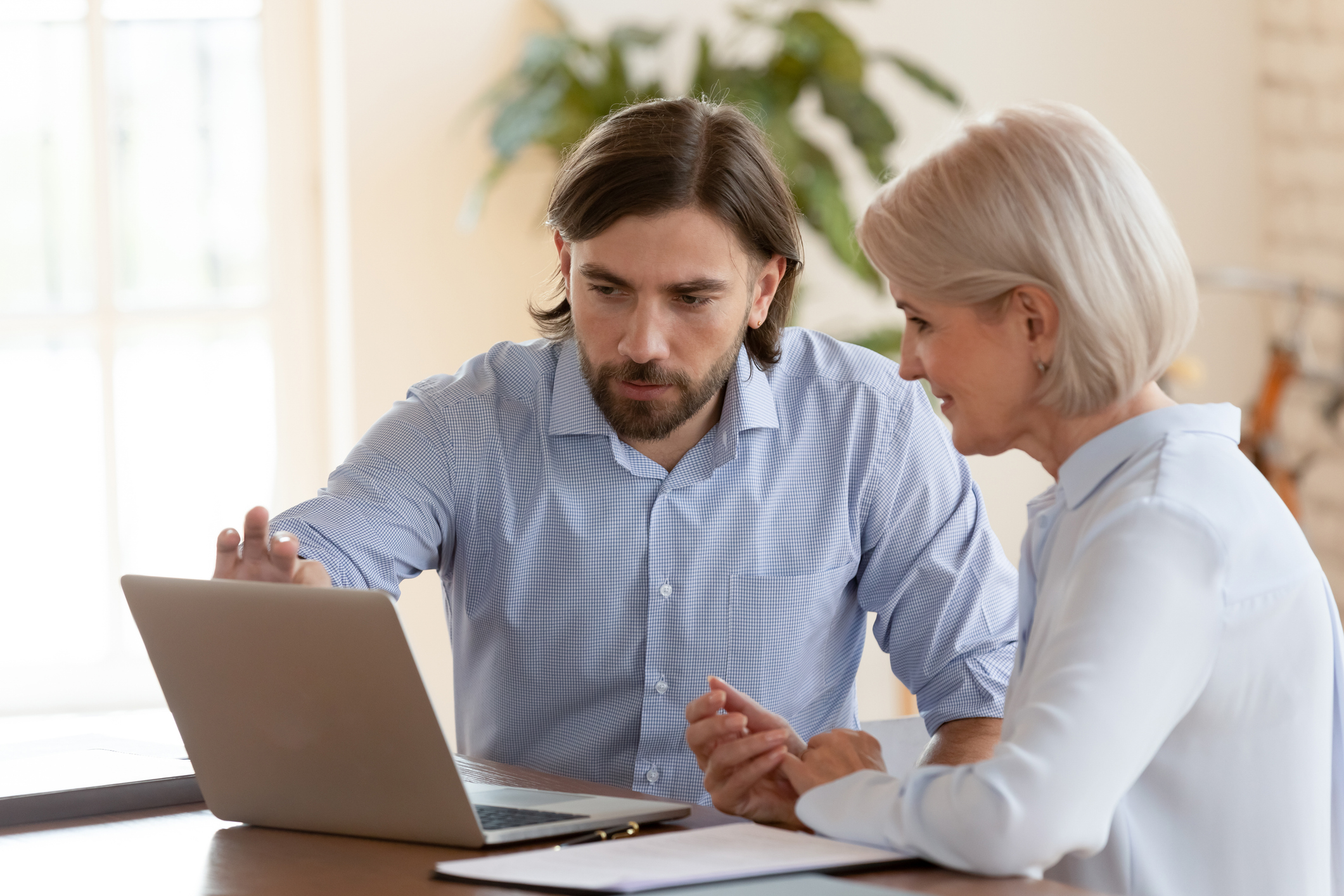 A man helping a woman use her laptop
